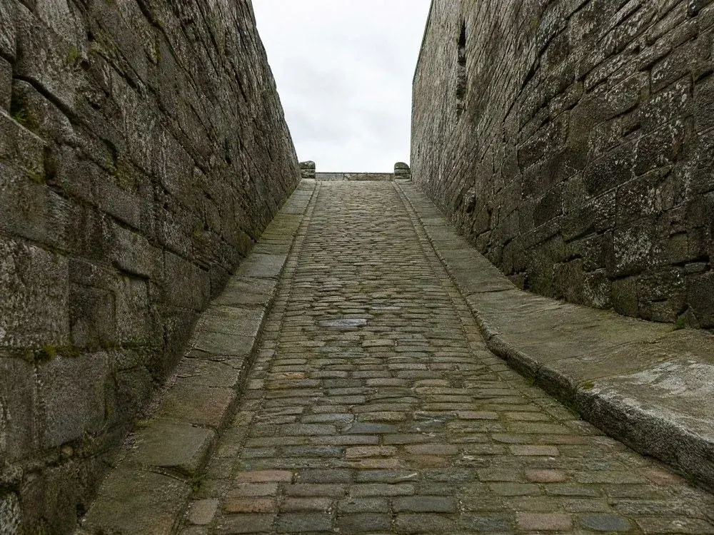 A cobbled ramp climbing between high stone walls
